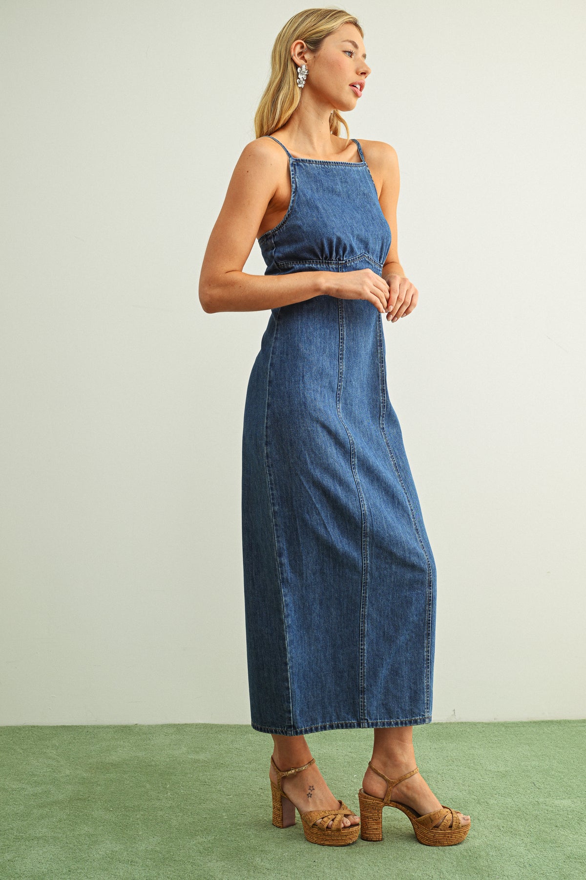 Woman wearing a blue denim dress on a plain background