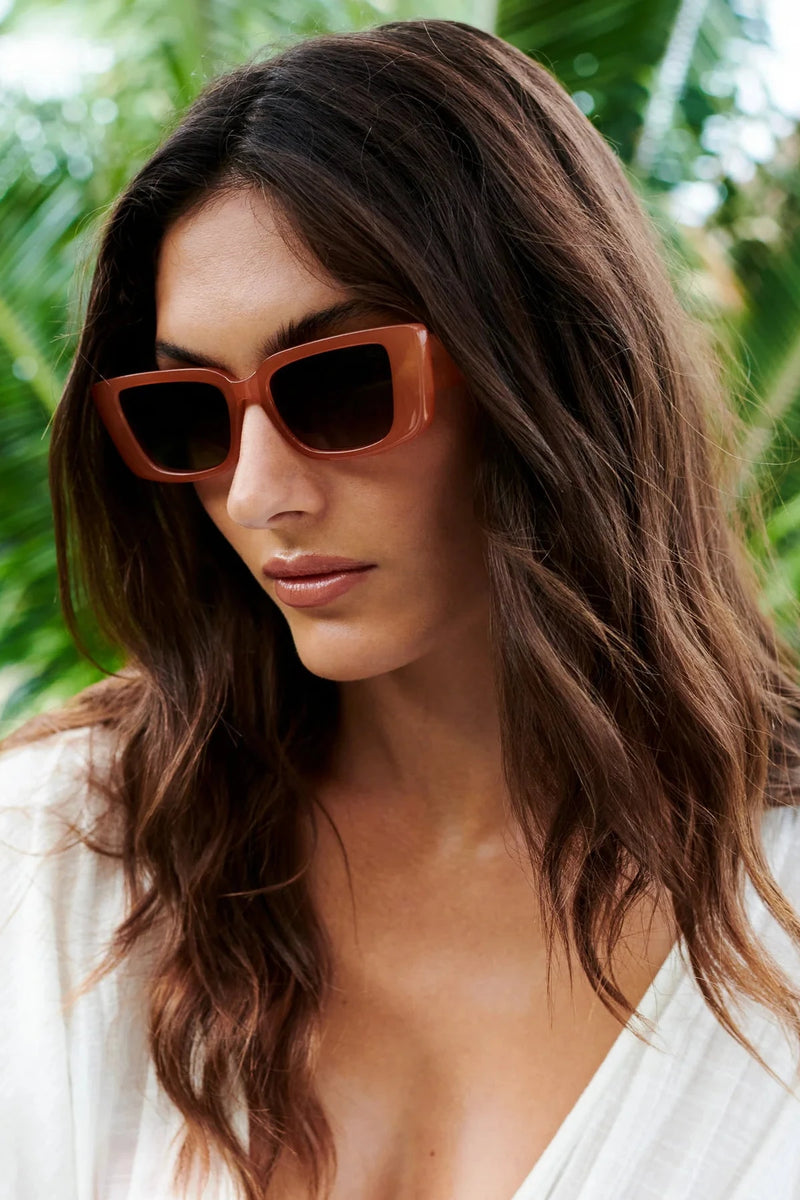 Woman wearing sunglasses with a tropical background