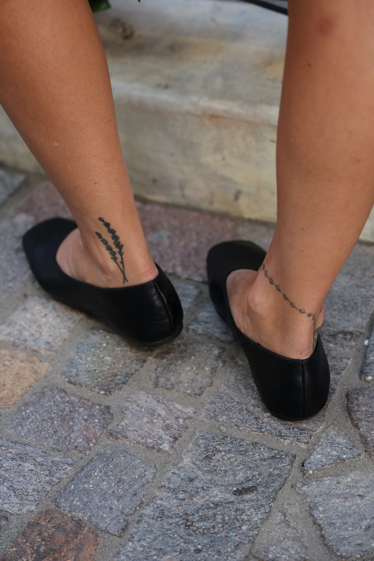 Woman wearing black flats on brick.