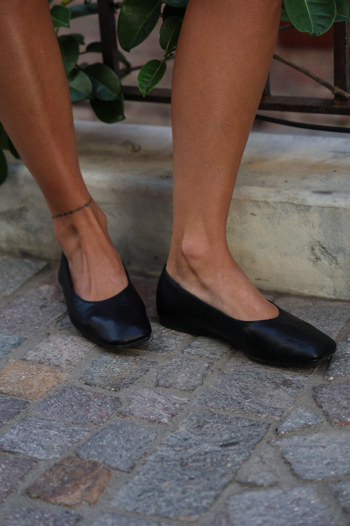 Woman wearing black flats on brick.