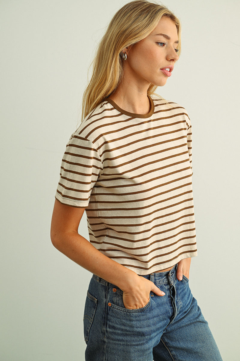 Woman wearing a striped shirt and jeans against a plain background