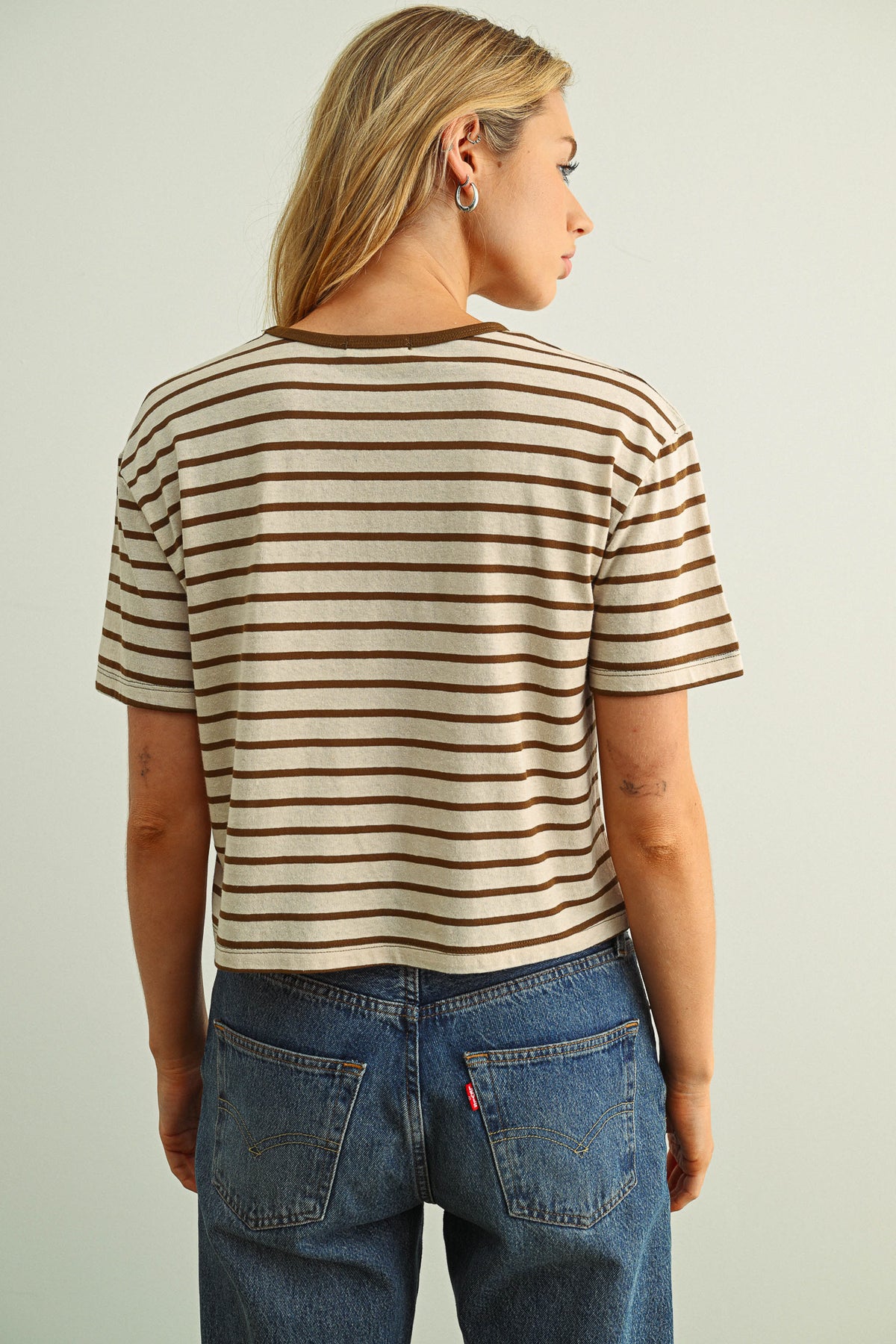 Person wearing a striped shirt and jeans against a plain background