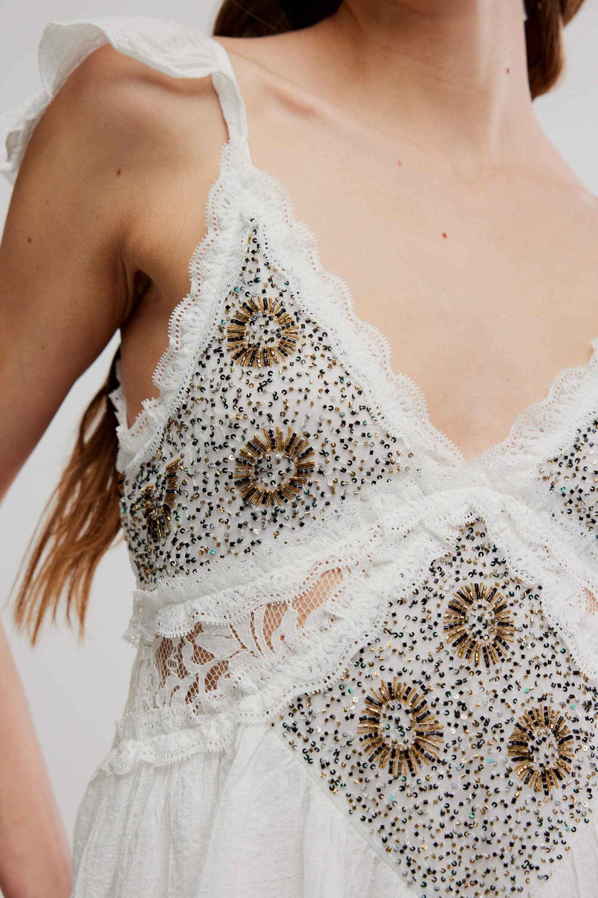 Close-up of a white lace dress with intricate black beadwork on a blurred background