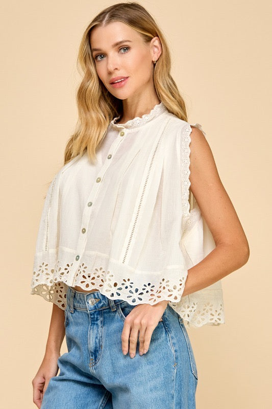 Woman wearing a white lace blouse and blue jeans on a beige background