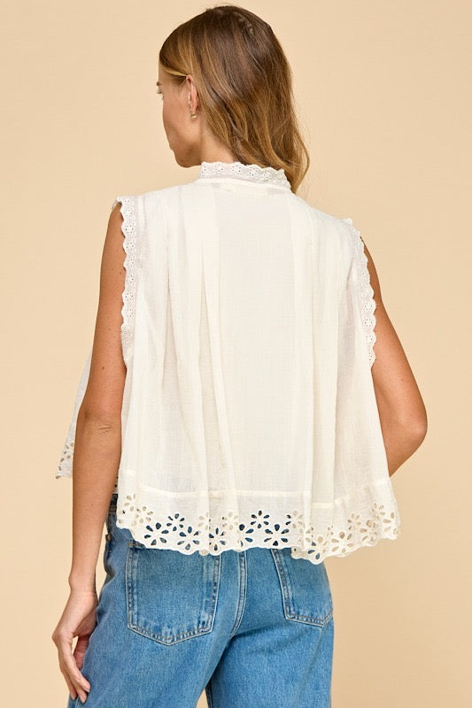 Woman wearing a white lace top and blue jeans on a beige background