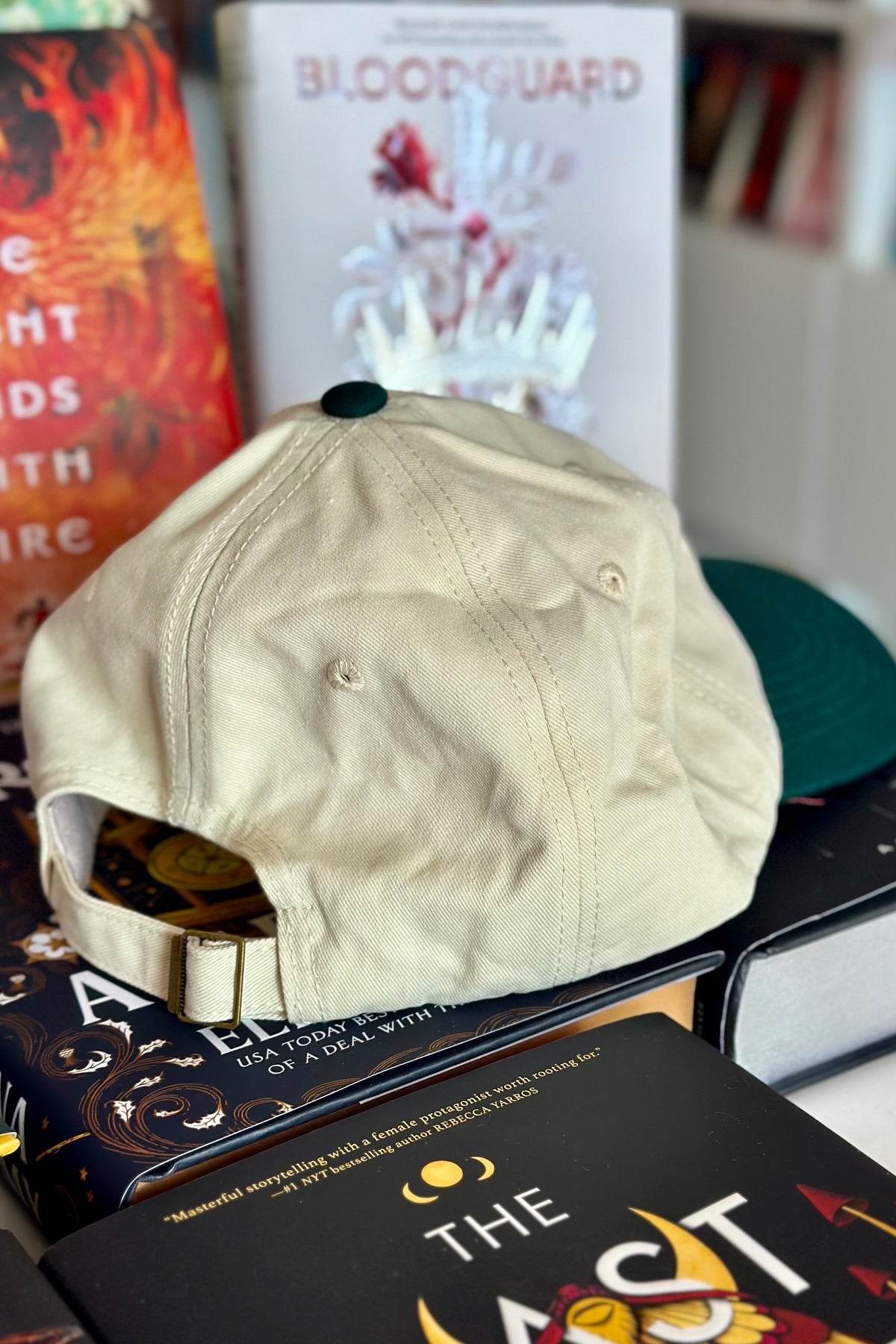 Beige cap on top of books with 'Bloodguard' book in the background