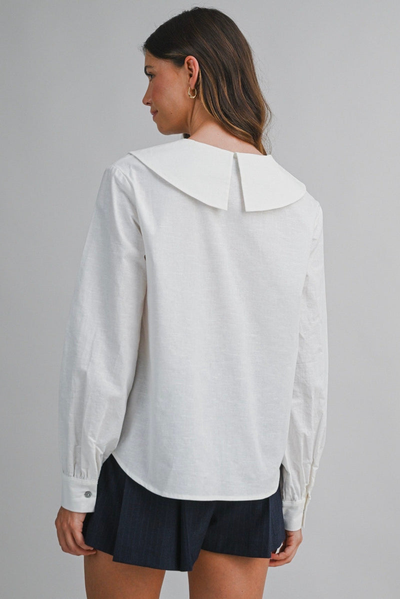 Woman wearing a white blouse with a collar on a gray background