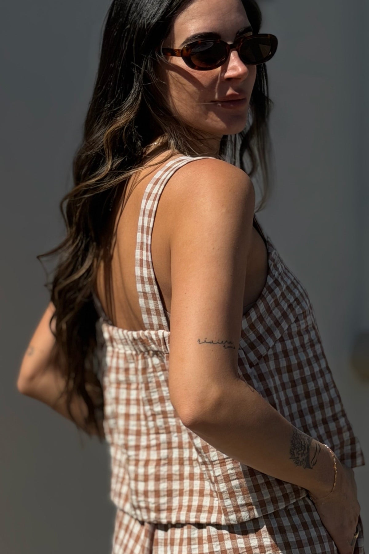 Woman wearing a checkered dress with a neutral background