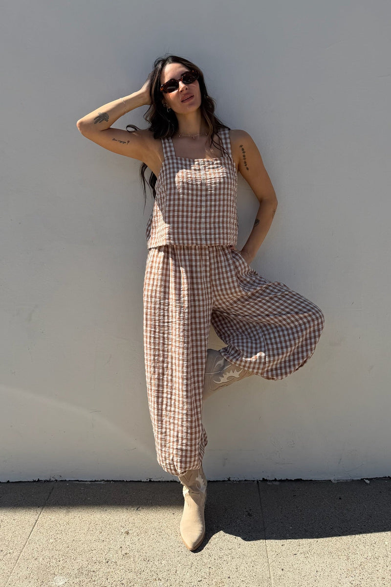 Woman in a checkered outfit posing against a white wall
