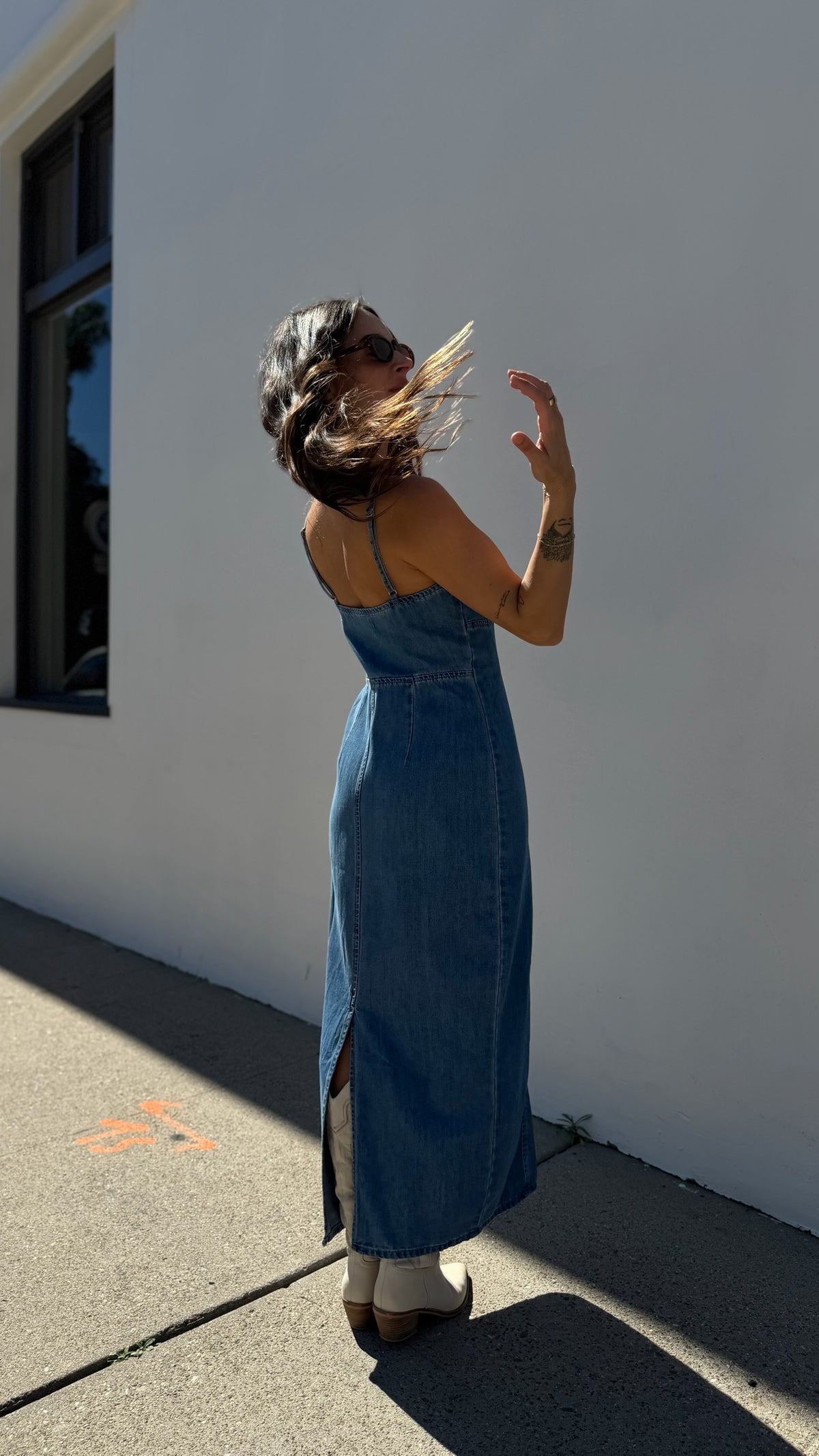 Woman in a blue dress standing against a white wall