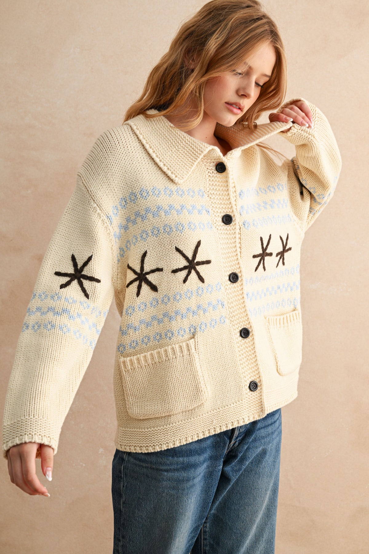 Woman wearing a beige knitted cardigan with star patterns on a beige background