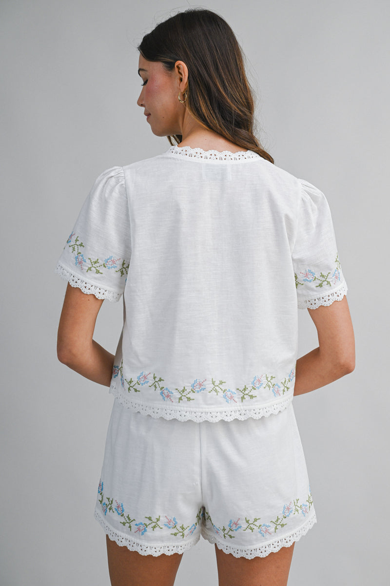 Woman wearing a white embroidered outfit on a gray background