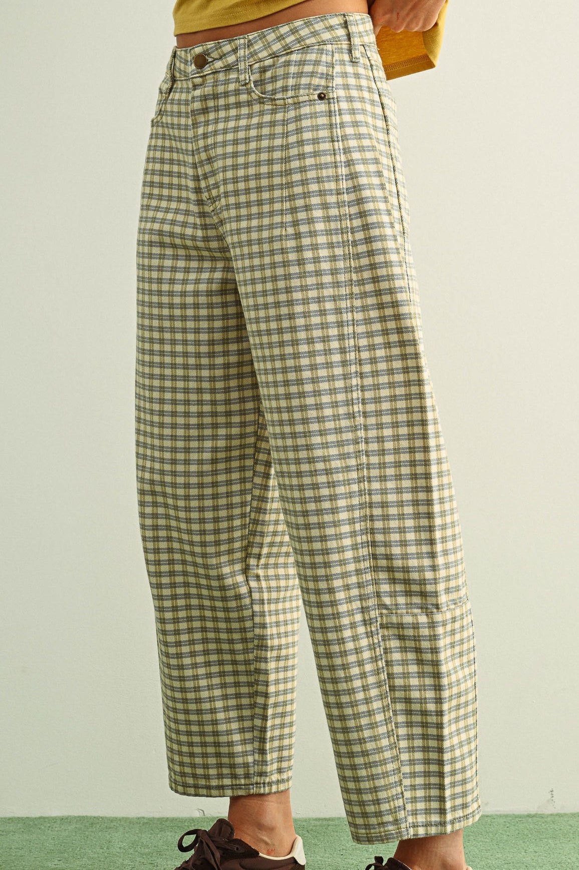 Person wearing green plaid pants with a plain background