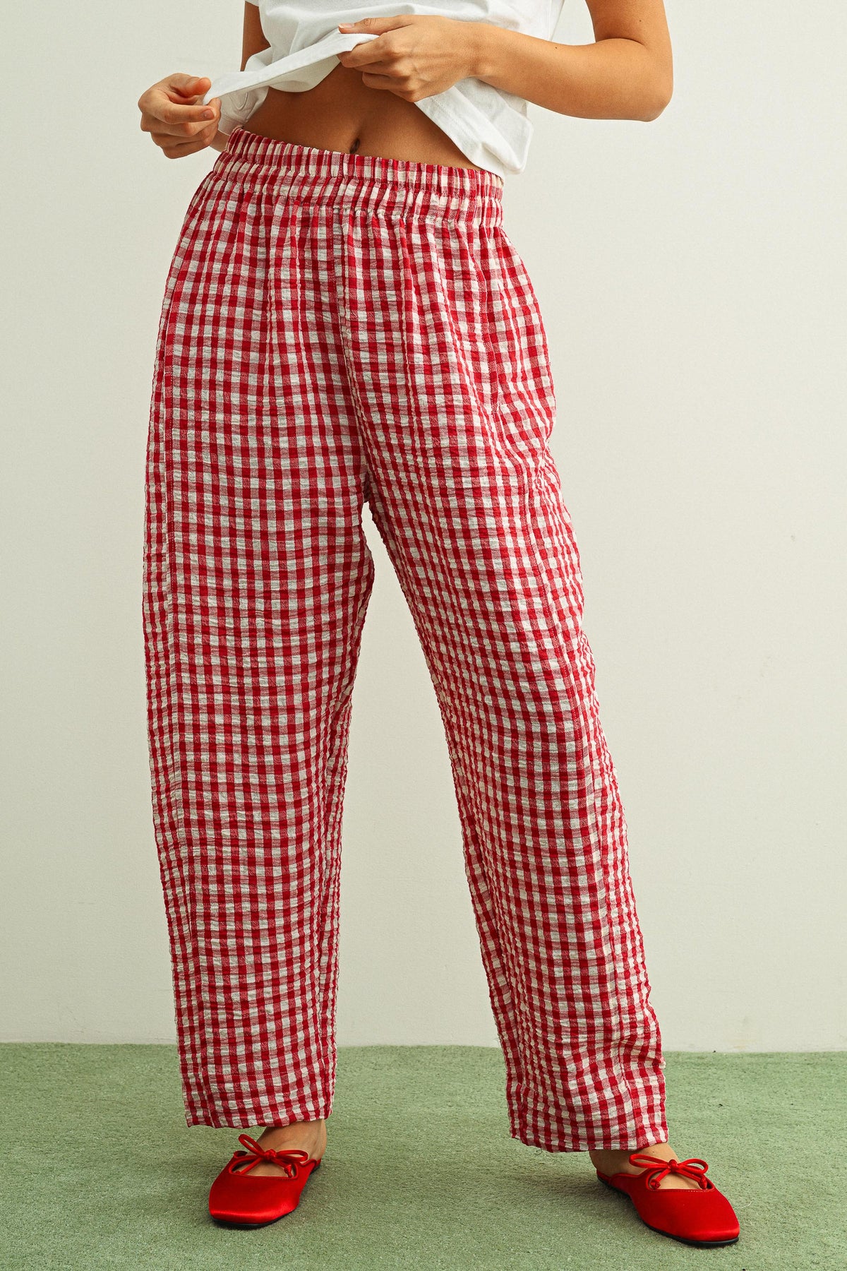 Woman wearing red gingham pants against a white background