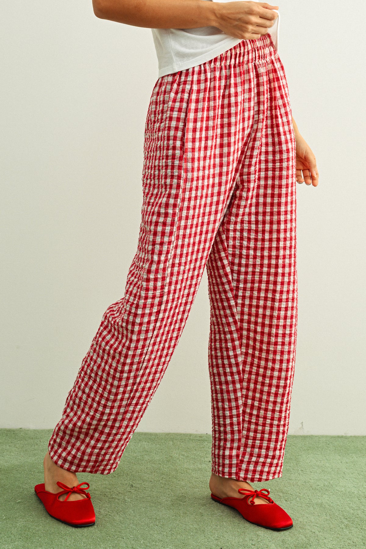 Woman wearing red gingham pants against a white background