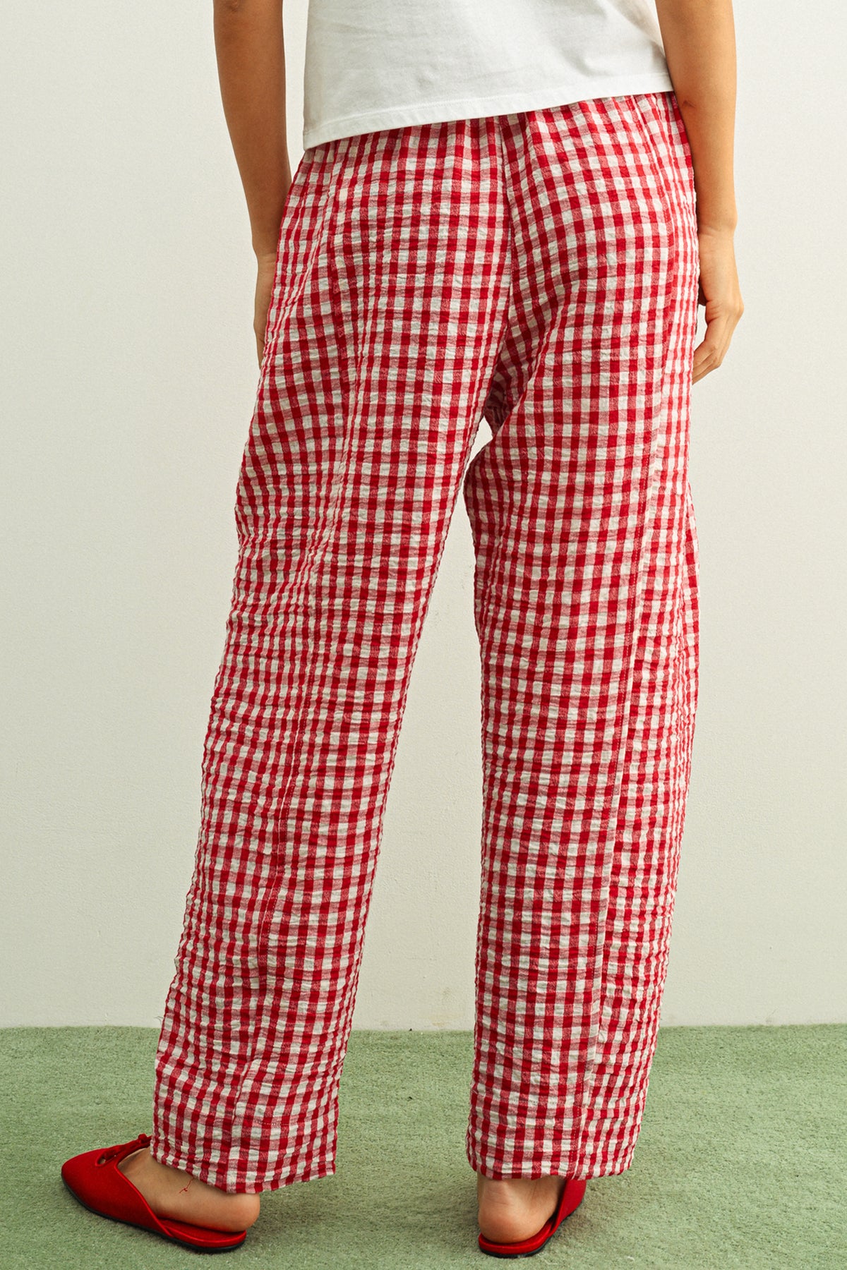 Woman wearing red gingham pants against a white background