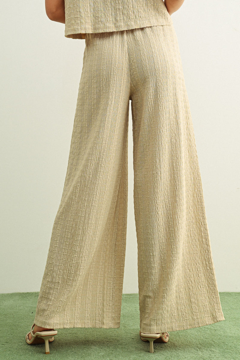 Beige textured pants worn by a person on a green surface with a neutral background