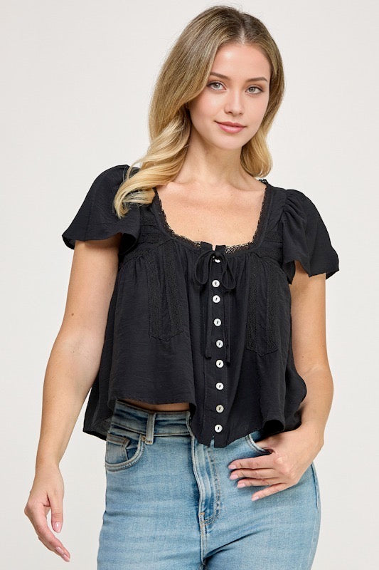 Woman wearing a black blouse with white buttons against a studio background