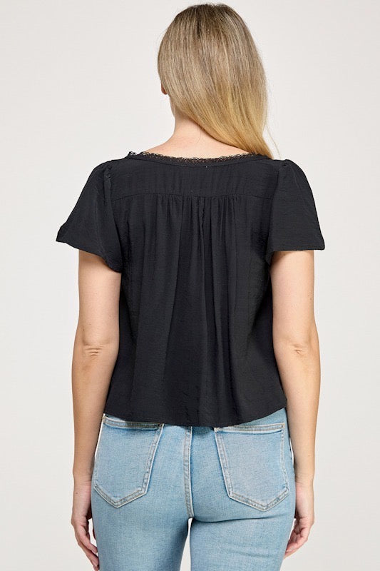 Woman wearing a black blouse with white buttons against a studio background