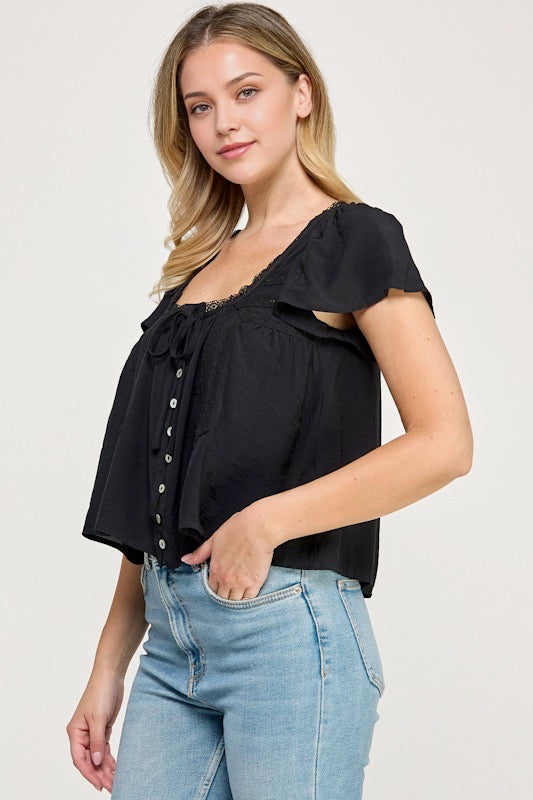 Woman wearing a black blouse with white buttons against a studio background