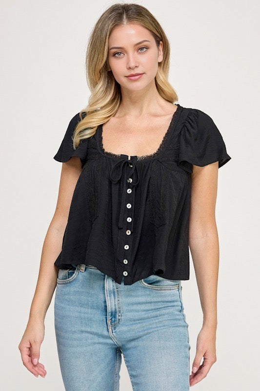 Woman wearing a black blouse with white buttons against a studio background
