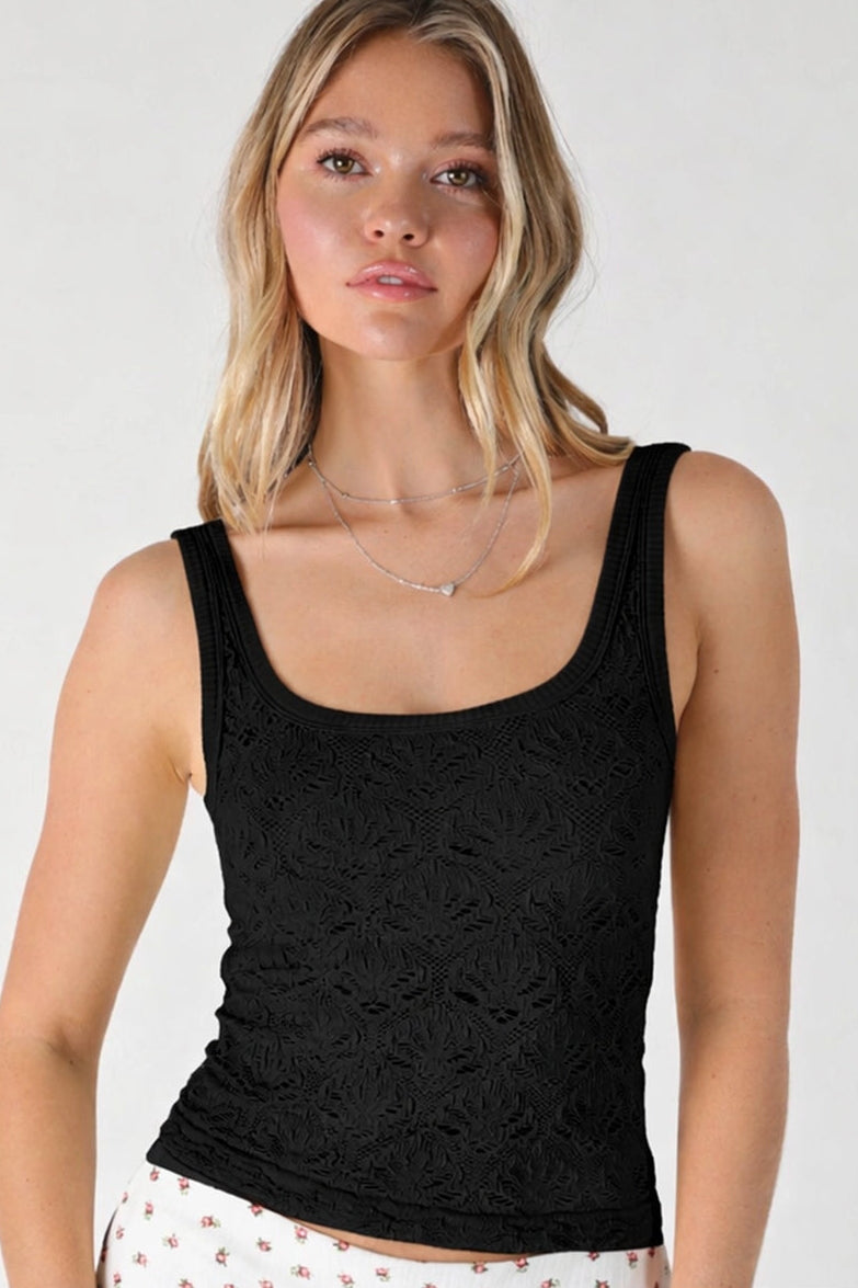 A woman wearing a black sleeveless scoop-neck tank top with a textured floral lace-like pattern, paired with white patterned shorts. The image has a white background and a '6 BLACK' label overlay in the bottom right corner.