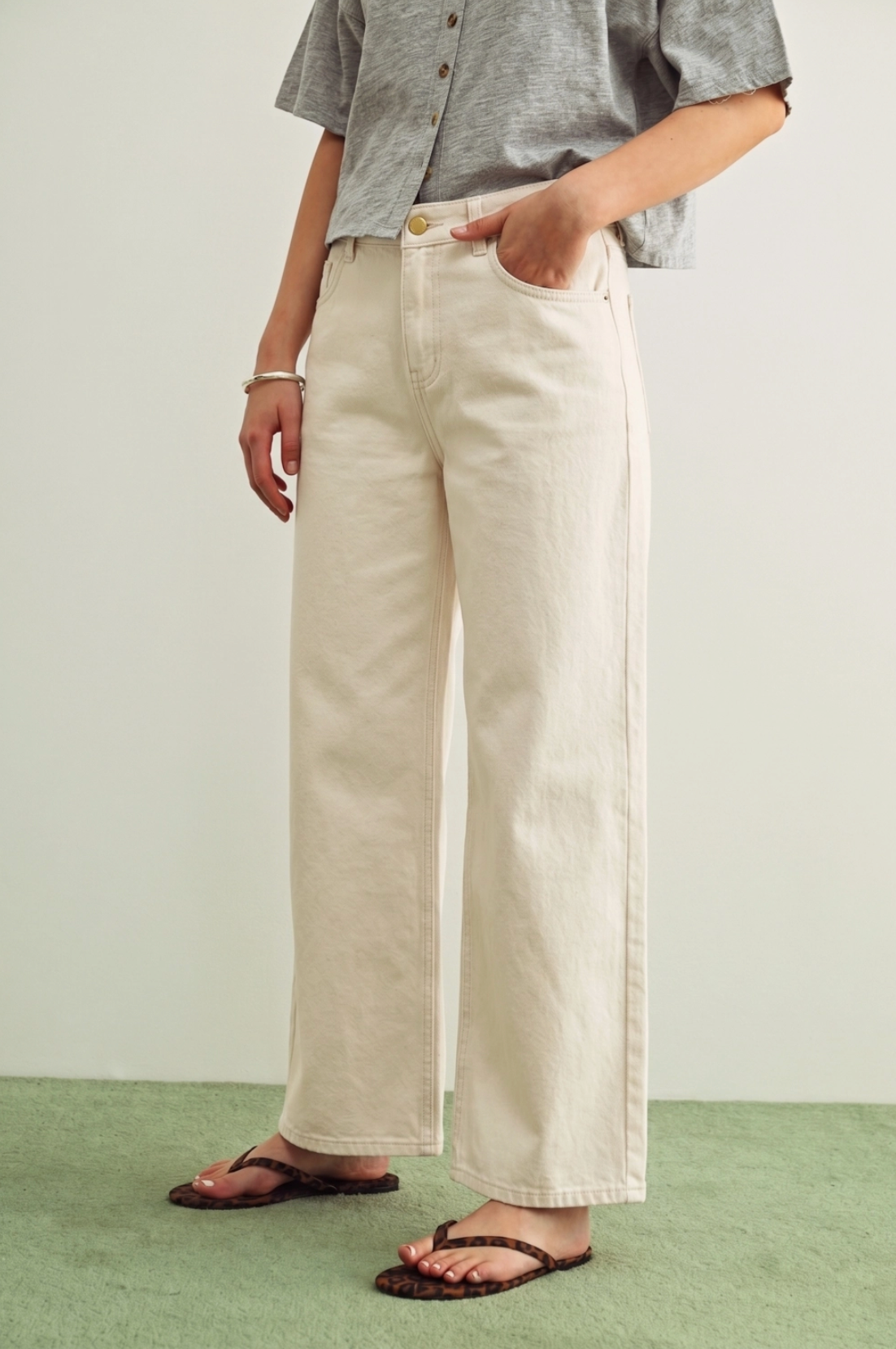 Person wearing light-colored wide-leg pants and a gray shirt on a plain background