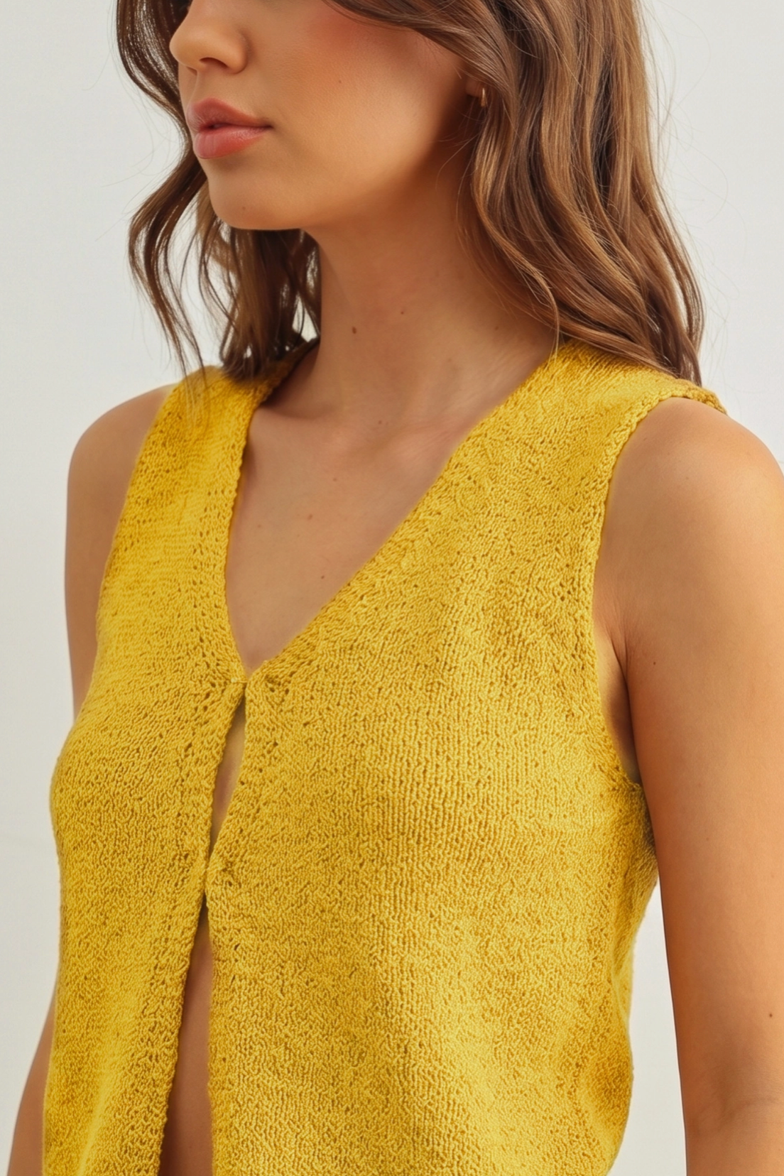 Yellow sleeveless top worn by a person on a plain background