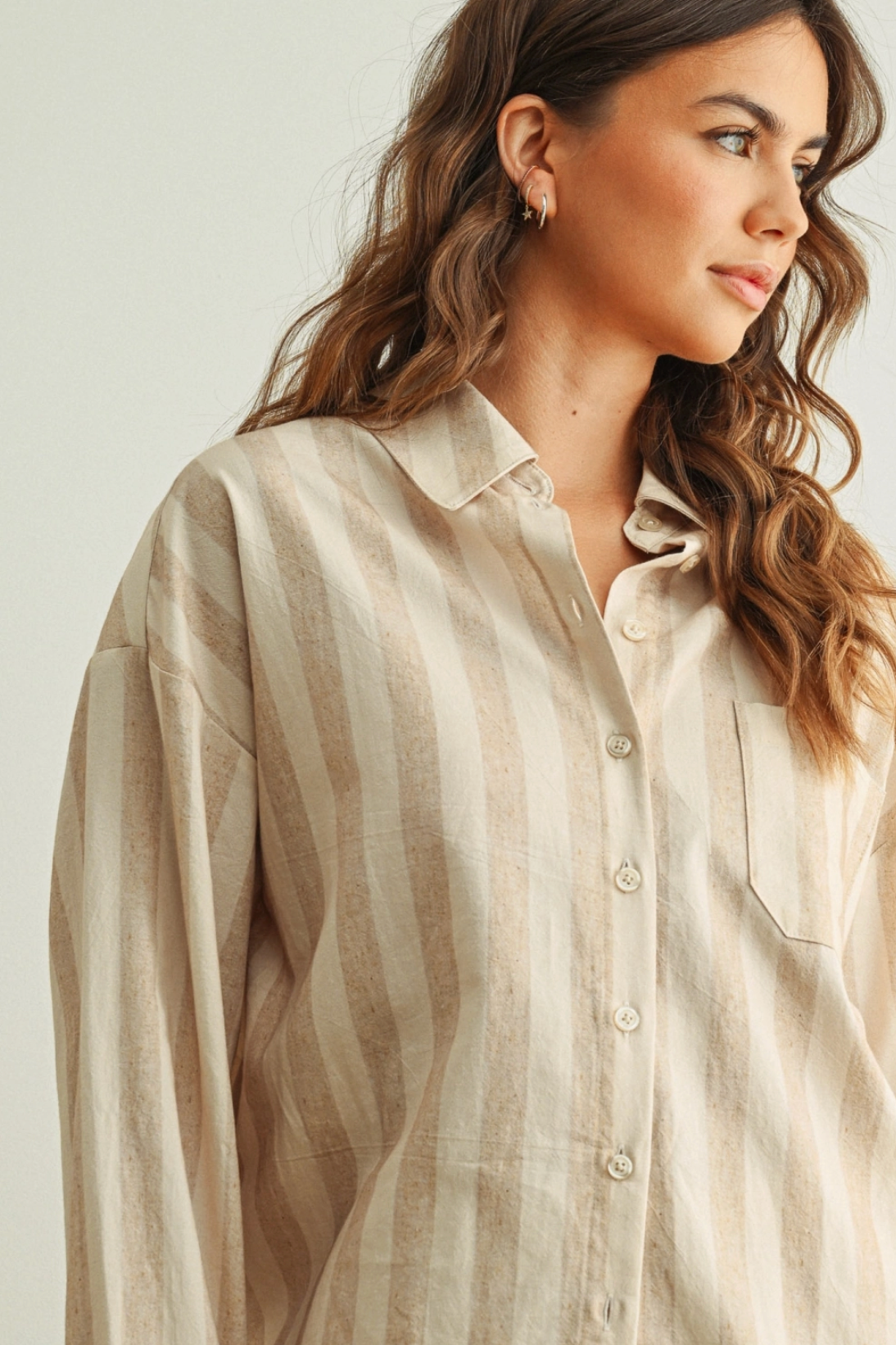 Woman wearing a beige striped shirt against a plain background