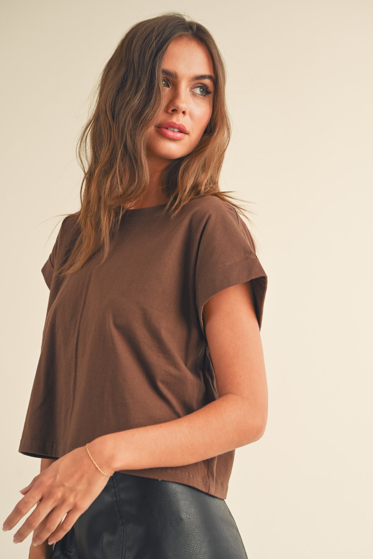 Woman wearing a brown top against a beige background