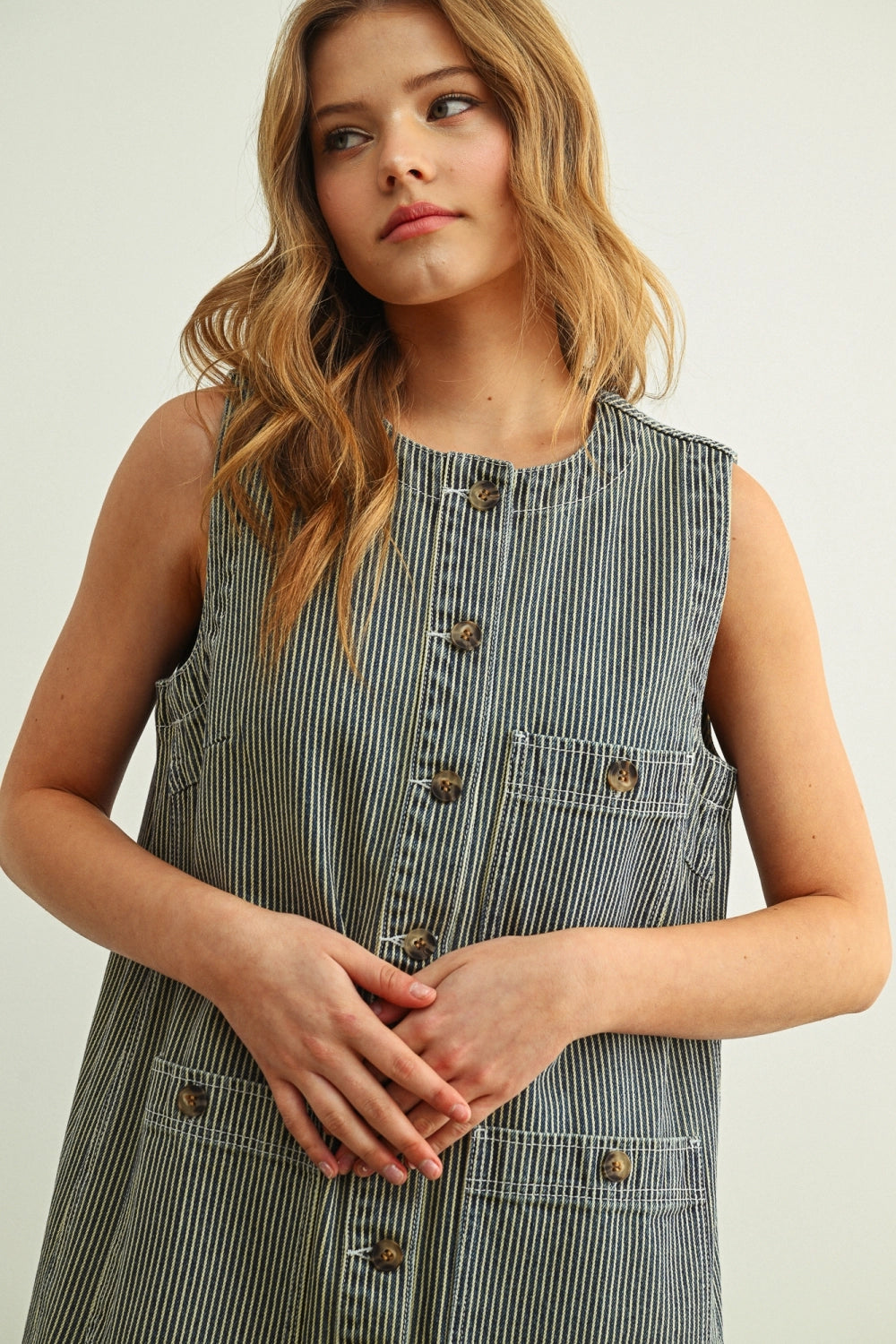 Woman wearing a striped dress with buttons on a plain background