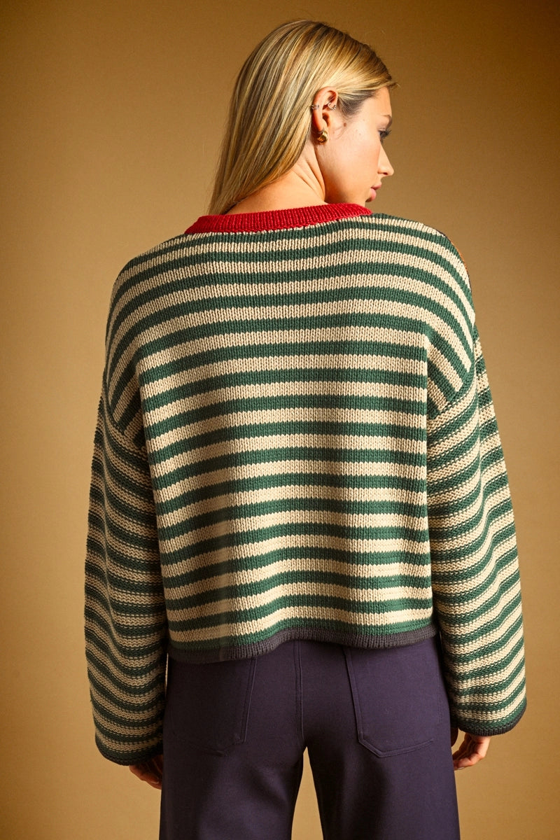 Woman wearing a colorblock knit striped swear with blue trousers against a plain background