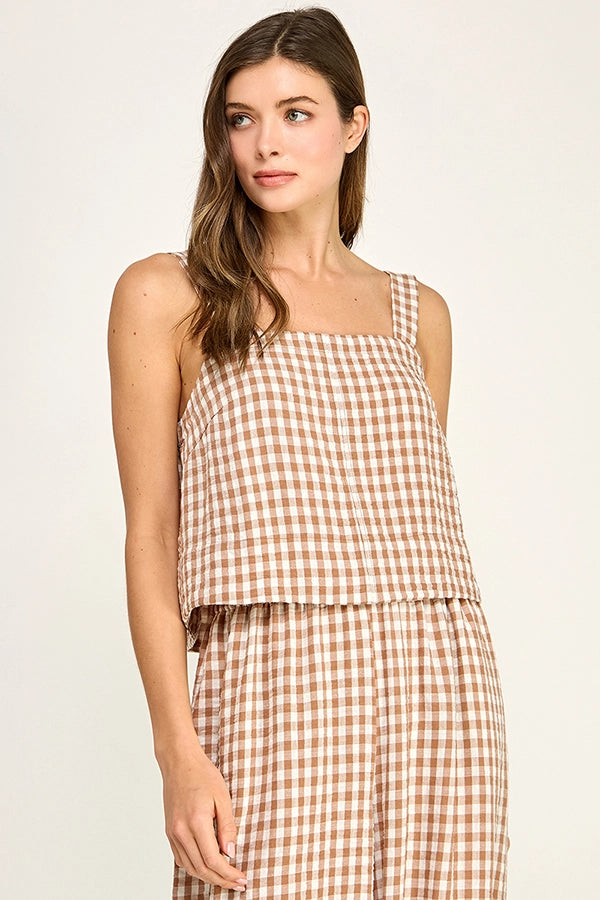 Woman wearing a brown and white checkered top and skirt on a plain background