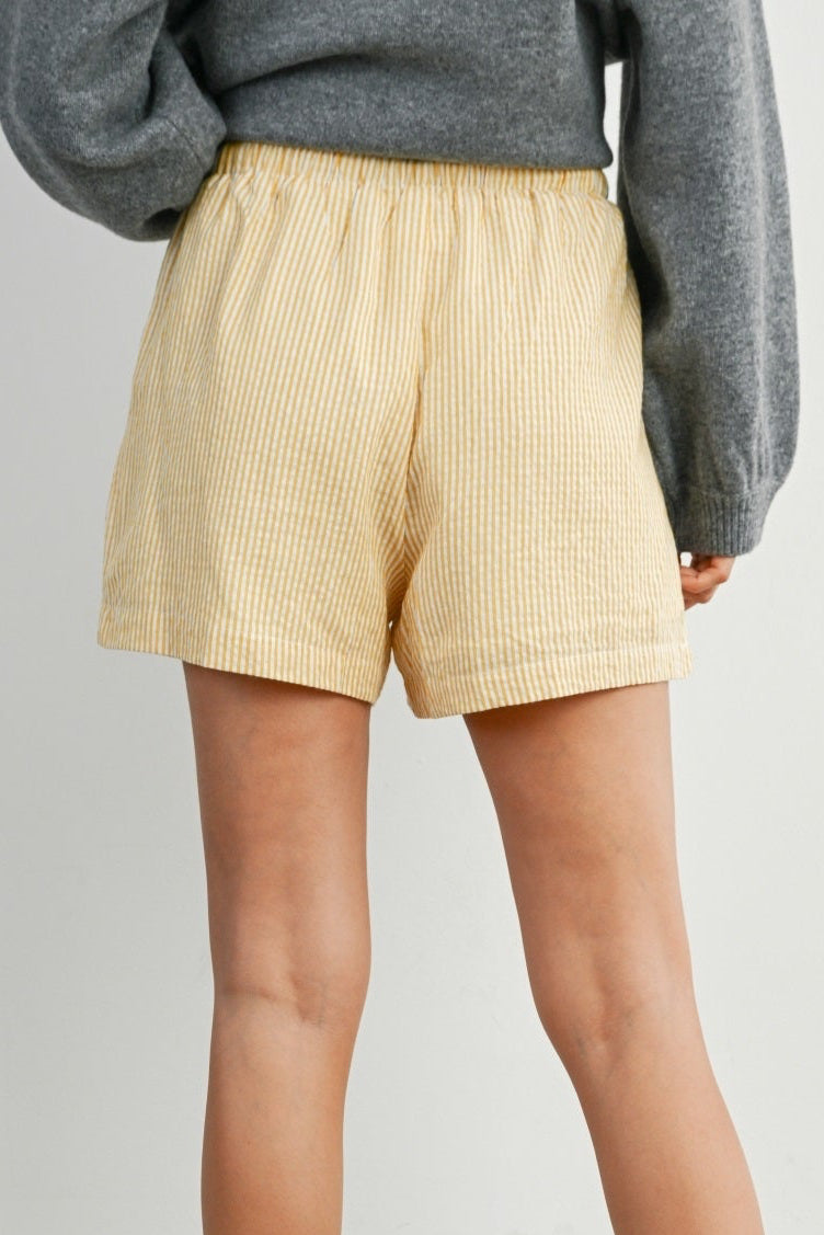Person wearing yellow shorts and white socks on a plain background