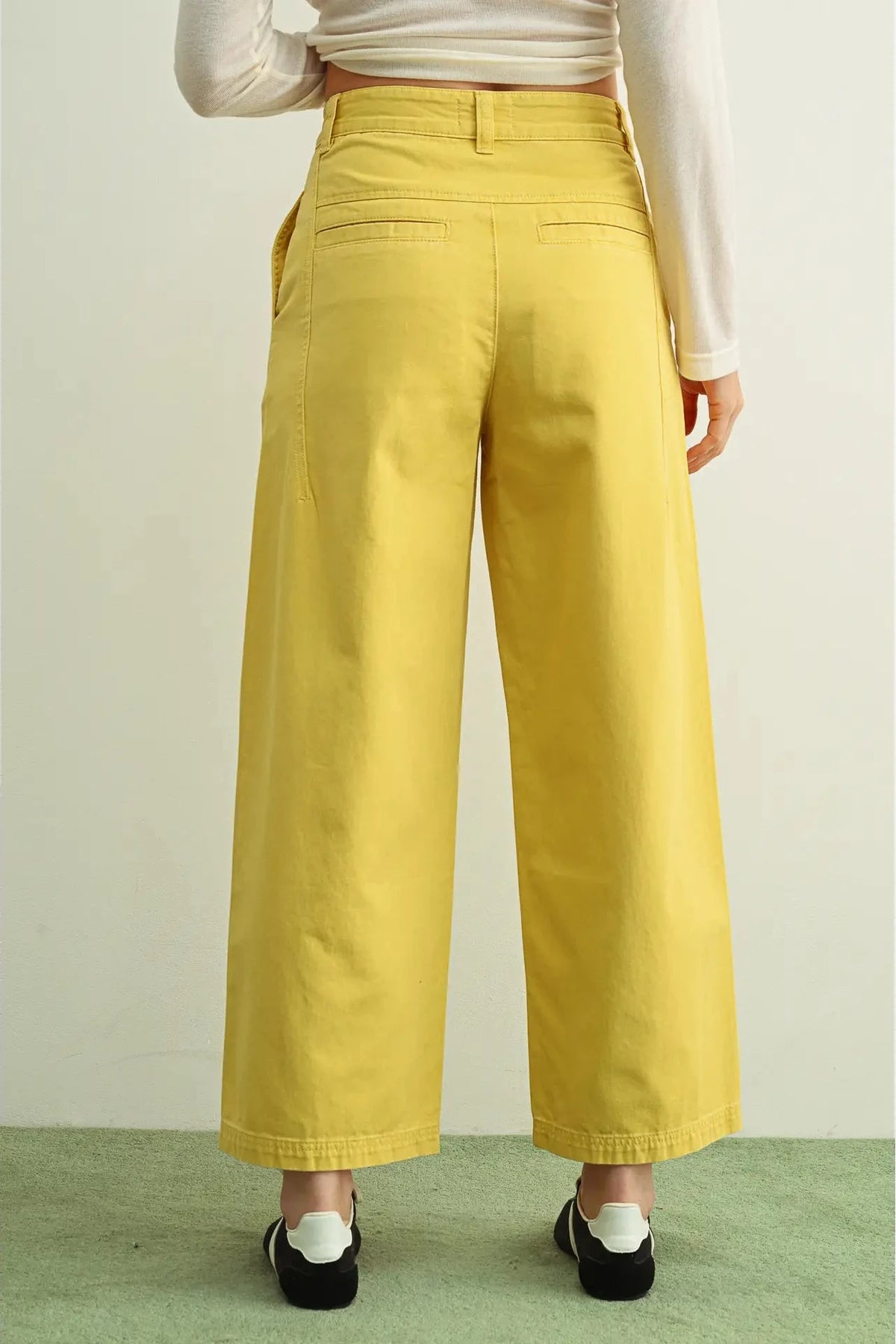 Person wearing mustard yellow wide-leg pants on a plain background