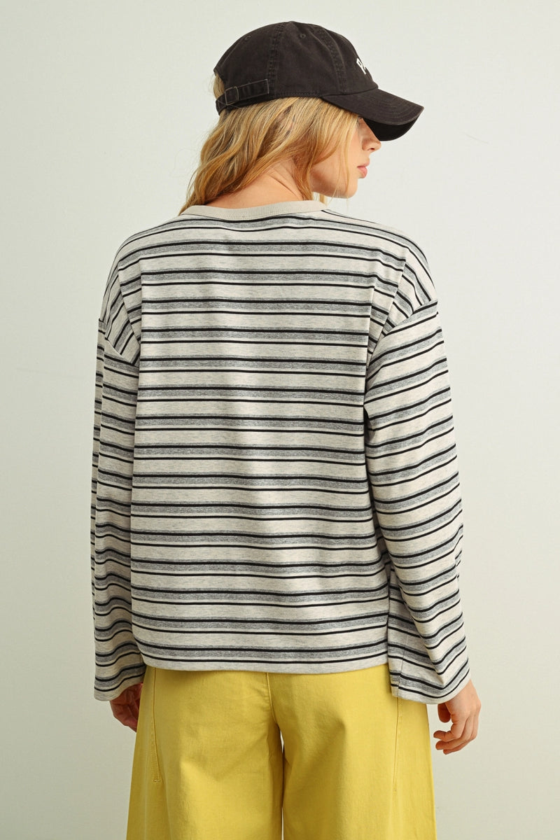 Person wearing a striped long-sleeve shirt and yellow pants on a plain background