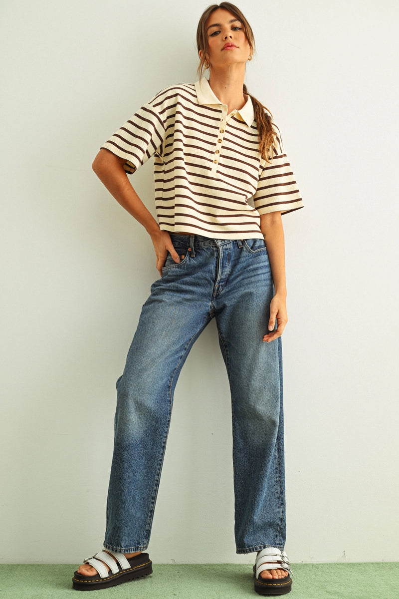 Woman wearing a striped shirt and jeans against a plain background