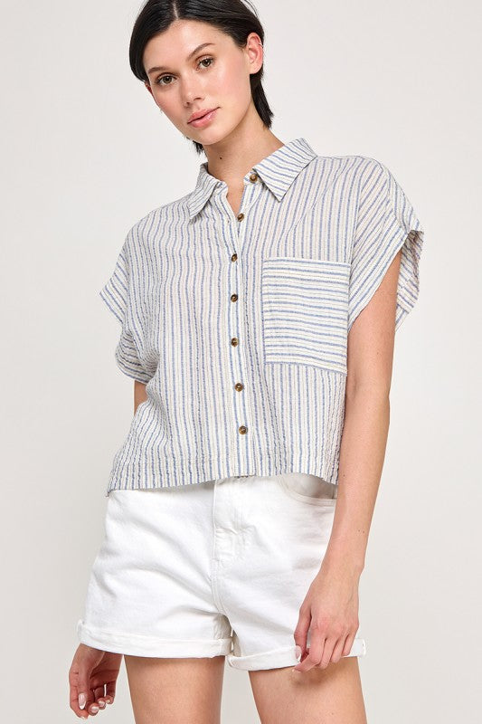 Woman wearing a striped shirt and white shorts on a plain background