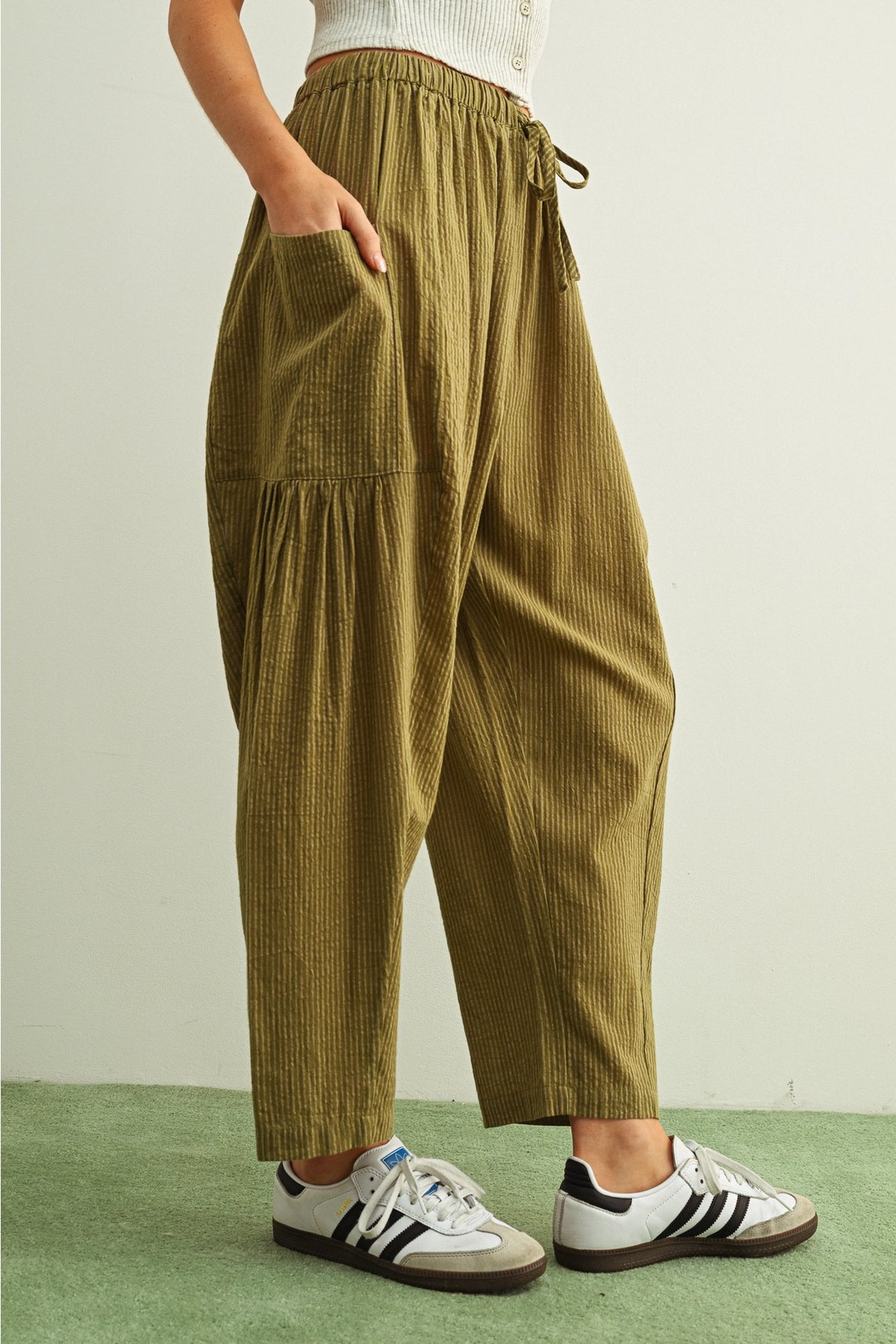 Person wearing olive green corduroy pants with a white background