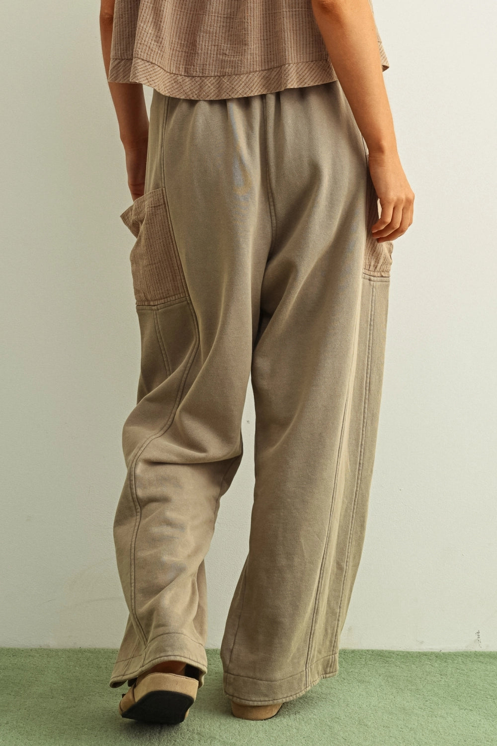 Person wearing beige pants and a matching top on a plain background