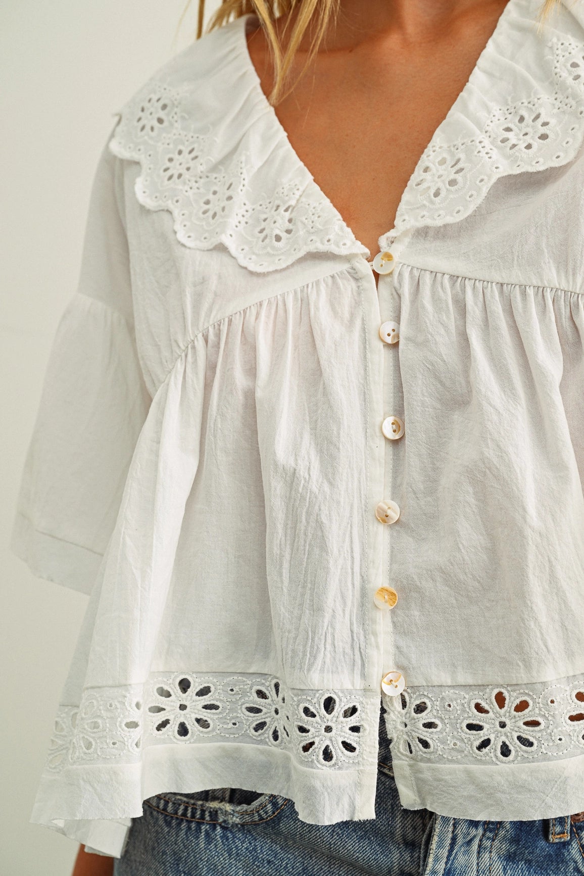 White blouse with lace details on a plain background