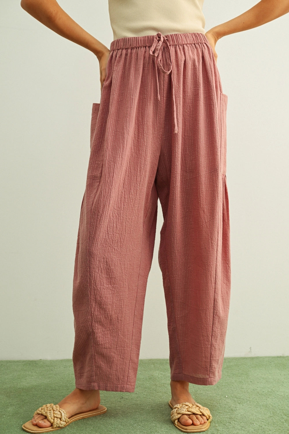 Person wearing pink textured pants on a plain background