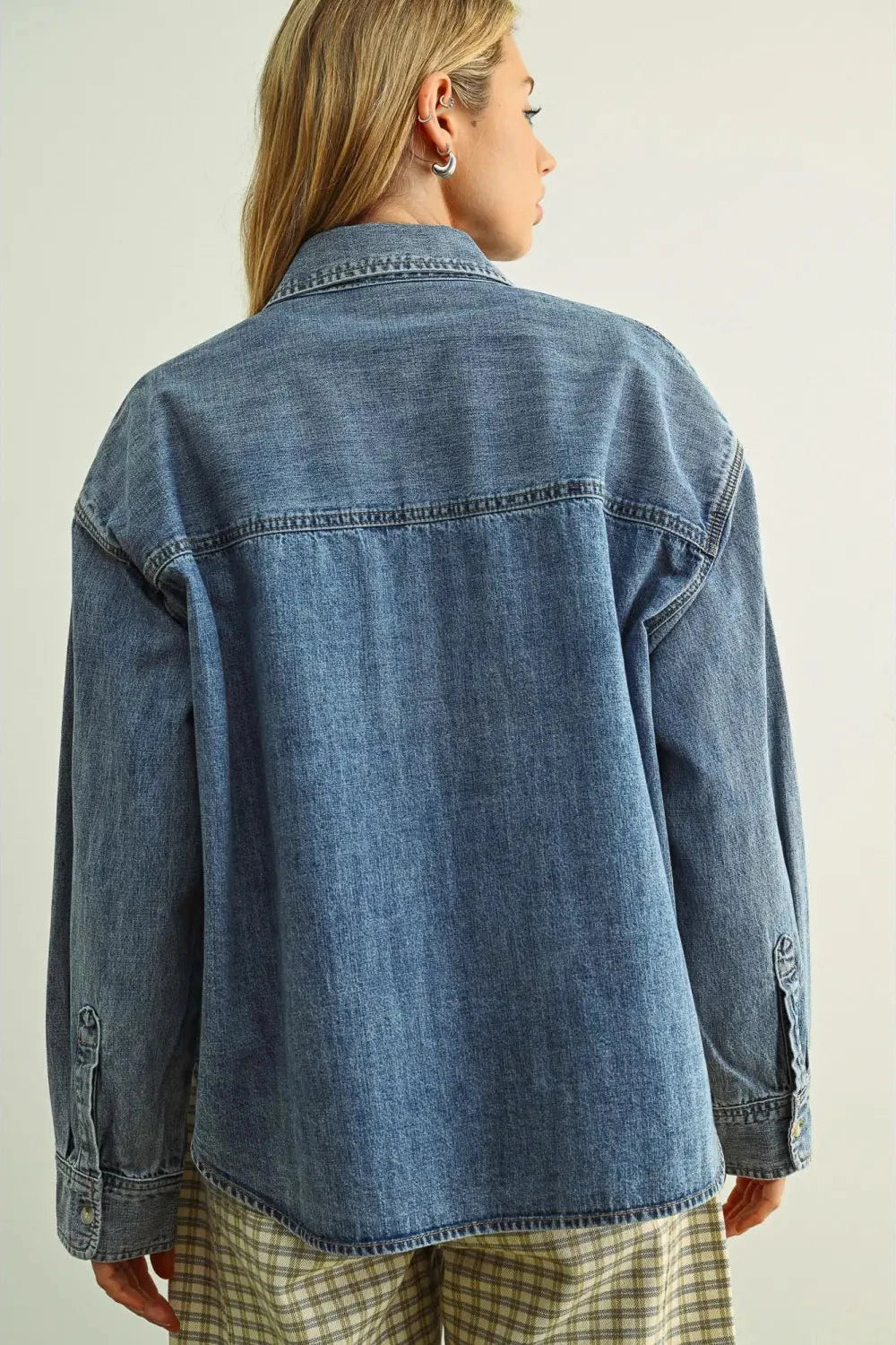 Person wearing a blue denim jacket on a plain background