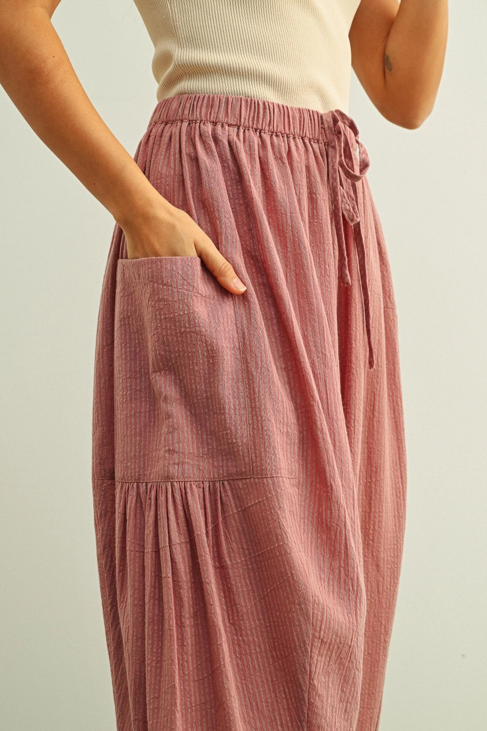 Person wearing a pink textured skirt with a neutral background
