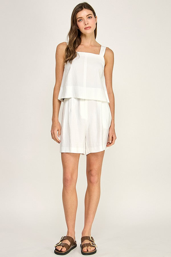 Woman wearing a white layered dress on a plain background