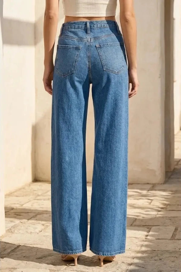 Person wearing blue wide-leg jeans in a sunlit outdoor setting