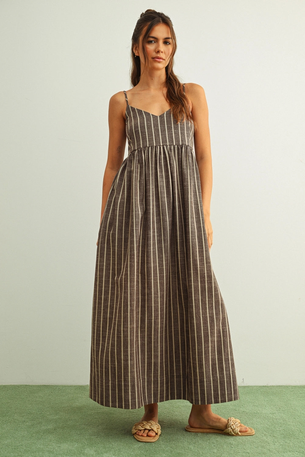 Woman wearing a striped dress standing against a plain background