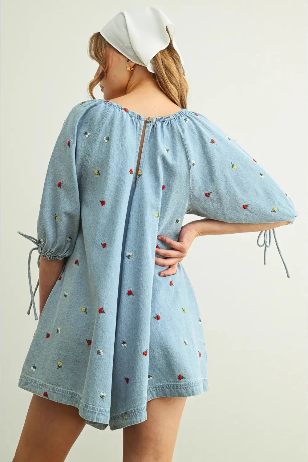 Woman wearing a light blue dress with heart patterns on a plain background