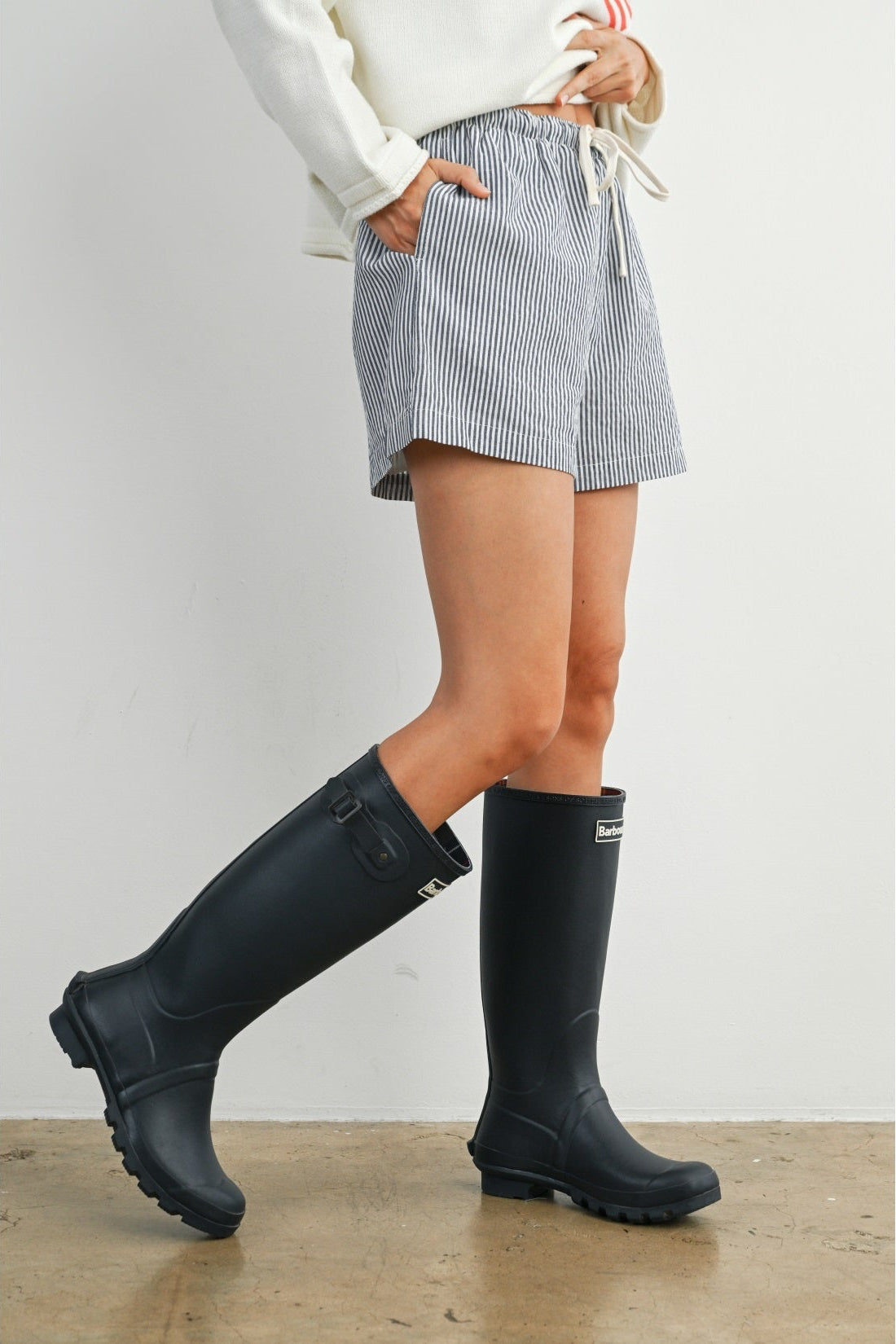 Person wearing black rain boots with a plain background