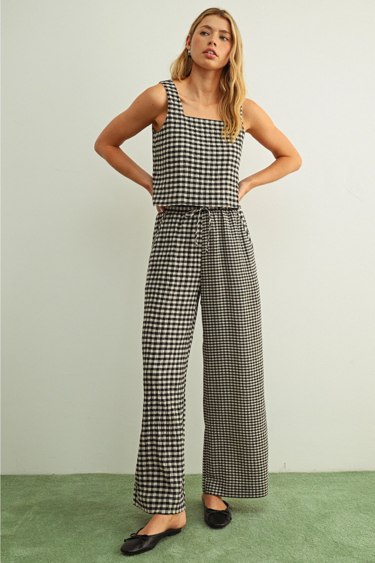 Woman wearing a black and white checkered jumpsuit against a plain background